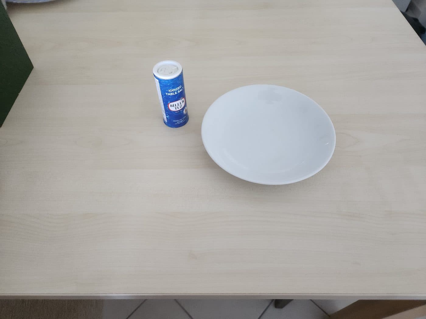 Phone photo of a plate and a salt shaker on a wooden table